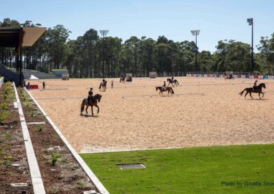 Six Horses being ridden at the Willinga Park show jumping arena with a view of the new grandstand and three new GM Poles sports lighting towers in the background.