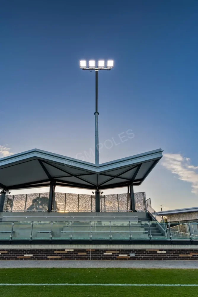 Sports lighting poles Australia illuminating a grandstand and sports field with LED luminaires at dusk